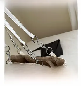 Detail of silver metal chain and white faux leather strap on beige woven tote bag