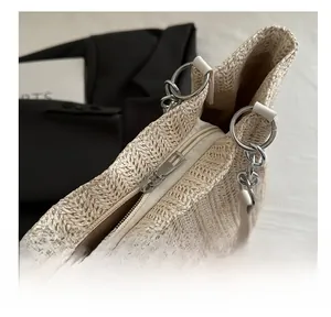 Close-up of the smooth metal zipper closure on this beige woven tote shoulder bag