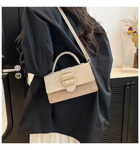 Beige Umhängetasche mit goldener Metallschnalle in minimalistischer Inneneinrichtung
