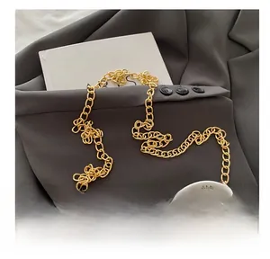 Detail of white quilted leather phone bag with elegant gold chain strap over grey blazer