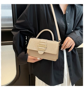 Détail d'un sac à main champagne avec rabat pailleté et boucle dorée porté par un mannequin