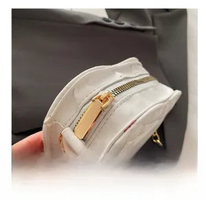 Detail of smooth gold zipper and white quilted leather texture on crossbody bag