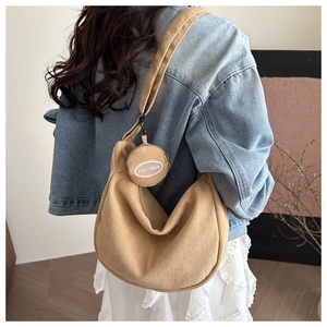 Close-up of khaki corduroy hobo bag with matching round coin purse detail shown on model