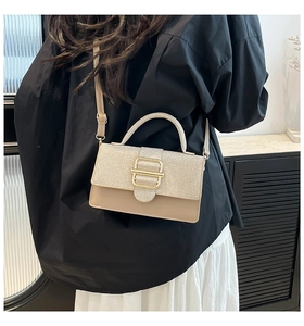 Détail d'un sac à main beige chic avec rabat scintillant et fermoir doré métallisé