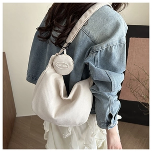 Detail view of off-white corduroy hobo bag texture and small circular coin purse