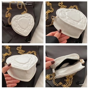 Detail view of heart-shaped quilted mini bag showing white faux leather and gold chain