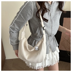 Detail of off-white waffle texture dumpling bag with a cute puppy pendant on model
