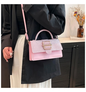 Sac à main rose en cuir verni et paillettes avec boucle dorée dans un décor élégant