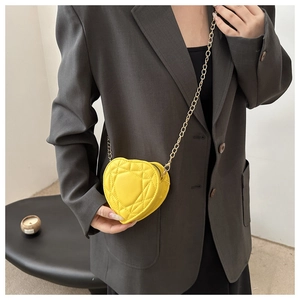 Detail of yellow heart-shaped mini bag with cannage quilting and gold chain strap