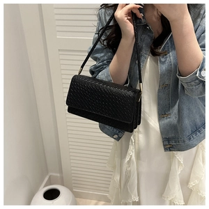 Detail of black woven crossbody bag with quilted texture and golden metallic strap hardware