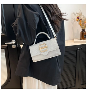 Détail du sac à main rectangulaire blanc avec texture tissée argentée et boucle dorée