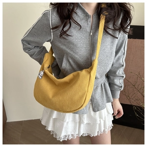 Detail of yellow corduroy crescent bag with smooth zipper and cute white dog charm
