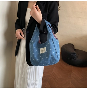 Detail der blauen Denim-Tasche mit weißen Schleifenmustern und süßem Bären-Patch