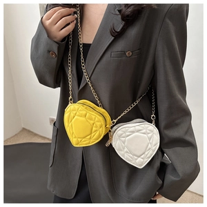 Detail of heart-shaped quilted mini chain bags in yellow and white faux leather