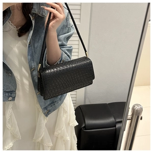 Close-up of black woven texture shoulder bag with elegant gold metal hardware details