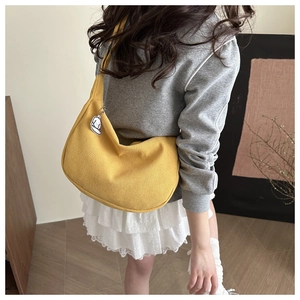 Detail der gelben Cord-Tasche mit süßem Hund-Anhänger am Model in lässigem Outfit