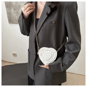 Detail of white heart-shaped crossbody bag with quilted pattern and gold chain strap