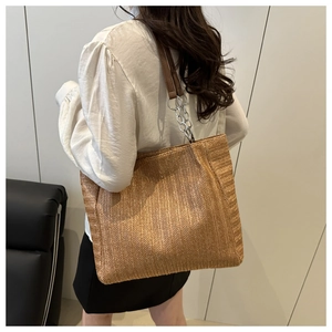 Detail of woven straw tote bag with brown leather and silver chain shoulder strap