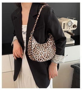Detail of leopard print hobo shoulder bag with gold hardware on a model in a cafe