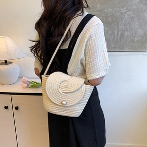 Chic cream woven shoulder bag with pearl clasp, shown as crossbody style on model