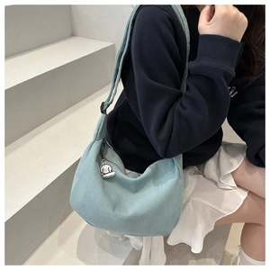 Close-up of light blue waffle-knit crossbody bag with a cute white dog plush charm