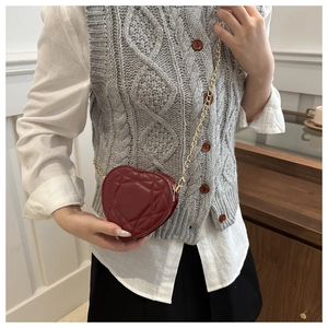 Detail of wine red heart-shaped bag with quilted pattern and gold chain strap