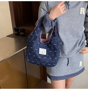 Detail der blauen Jeans-Handtasche mit Bärenstickerei, Herzprint und rot gestreiftem Futter