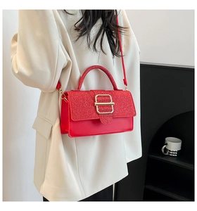 Détail d'un sac à main rouge avec rabat à paillettes et boucle dorée porté par un modèle