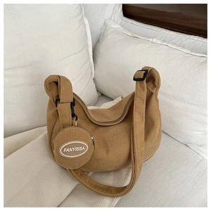 Detail of brown corduroy crescent bag with a detachable round coin purse on a soft pillow