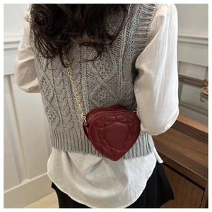 Detail of burgundy heart-shaped crossbody bag with gold chain and cannage quilting