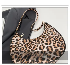 Close-up of leopard print crescent bag with golden zipper and textured fabric detail
