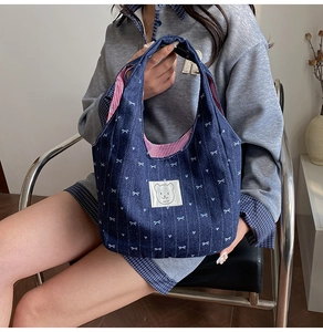 Detail der Jeans-Tote-Bag mit Schleifendruck und Bärenetikett sowie gestreiftem Innenfutter