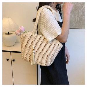 Detail of woven beach tote featuring white cotton fringe with wooden beads and flowers