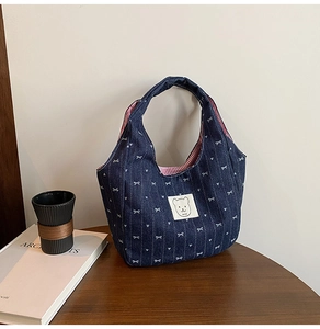 Detailaufnahme der Jeans-Handtasche mit weißen Herz-Schleifen und rotem Streifenfutter