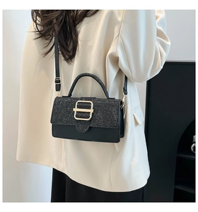 Détail d'un sac à main noir avec panneau à paillettes et boucle métallique dorée en gros plan