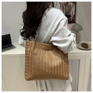 Detail der gewebten Stroh-Tasche mit elegantem Metallkettenriemen und feiner Textur