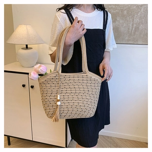 Detail of woven cotton rope tote bag featuring decorative tassels and wooden bead accents