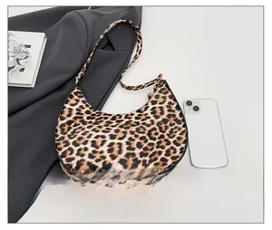 Detailed view of leopard print crescent bag next to a phone for size comparison