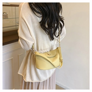 Detail shot of pale yellow litchi grain leather shoulder bag with metallic buckle closure