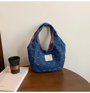 Detail der Jeans-Handtasche mit Schleifen-Stickerei und niedlichem Bären-Etikett