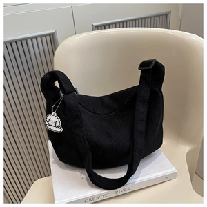 Détail du sac bandoulière en velours noir avec large sangle et pendentif chiot
