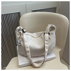 Détail du sac bandoulière en velours côtelé crème avec sangle réglable et pendentif peluche