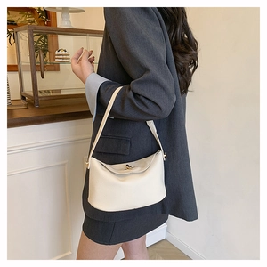 Detail of cream white leather bucket bag with gold clasp shown on a model