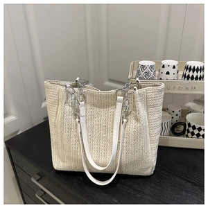Detailansicht der cremefarbenen Strohtasche mit Silberkette und Fischgräten-Webmuster-Textur