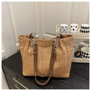 Detail der Strohtasche mit V-förmigem Webmuster und silbernem Kettenriemen