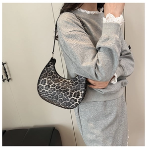 Detail of leopard print crescent moon bag with thin black shoulder strap on model