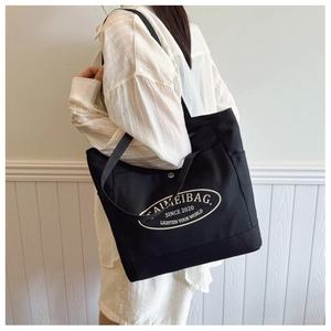 Side view of a large black canvas tote bag worn by a model for daily commuting