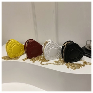 Detailed view of quilted heart-shaped chain bags in yellow, red, white, and black