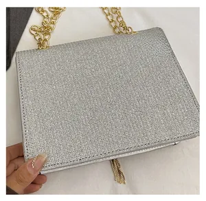 Detail of silver sequin evening bag with gold chunky chain strap and fringe tassels