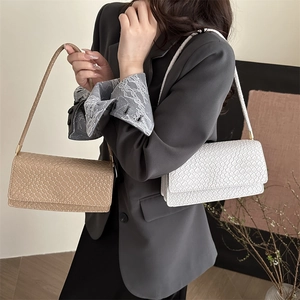 Minimalist woven shoulder bag in beige and white featuring a flap closure and slim strap